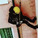 Lezec na laně při opravě fasády obytného domu za provozu