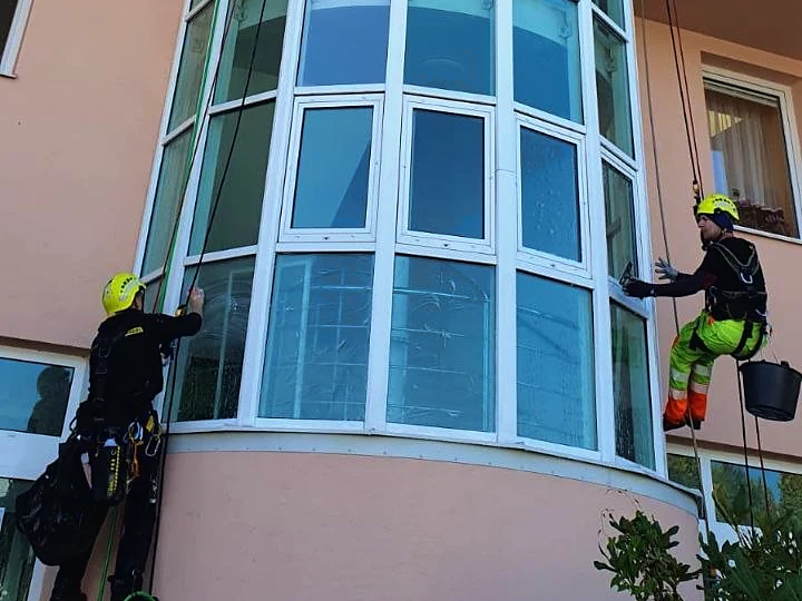 Dva lezci čistí skleněné atrium vedle hlavního vchodu do budovy G-centra v Táboře