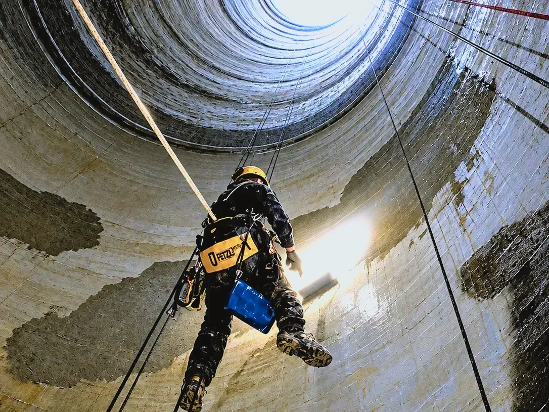 Nanášení epoxidové vrstvy z lan uvnitř 274 m vysokého průduchu, pracuje se ve visu